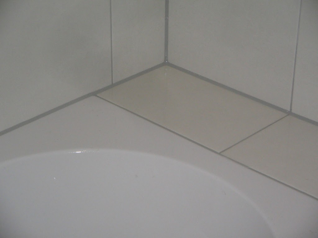 Close-up van een strakke witte kitvoeg tussen bad en wandtegels