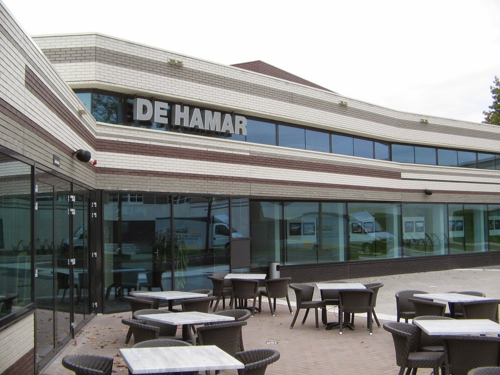 Gebouw De Hamar met een glazen gevel en een terras
