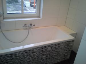 Bad met mozaïek ombouw onder het raam