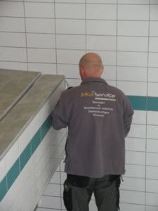 Vakman in een jas van JeKa Service aan het werk bij een zwembadrand